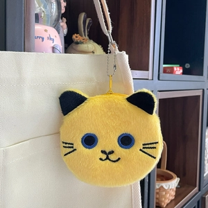 Detail of yellow plush cat coin purse with metal zipper hanging on a canvas bag