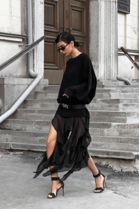 Detail of black knit top paired with irregular floral chiffon skirt in a street style look