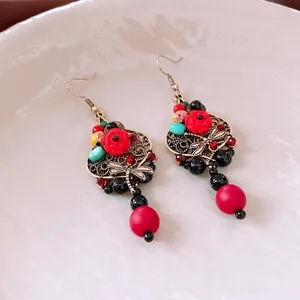 Vintage dragonfly earrings with red rose pendant and turquoise beads on ceramic plate