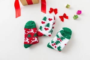 Detailed view of plush Christmas socks with reindeer and tree patterns on white surface