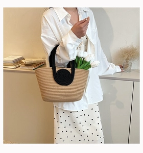 Detail of hand-woven beige cotton rope tote with black handles and floral decorations