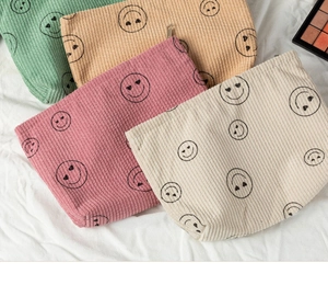 Detailed corduroy fabric texture and heart-eyed smiley face print on cosmetic pouches