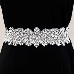 Macro detail of silver bridal belt with shimmering rhinestone floral and leaf patterns