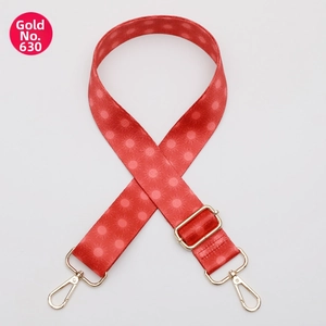 Macro shot of red jacquard bag strap with gold metal swivel hooks and dot pattern