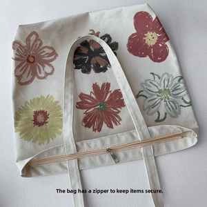 Detail of floral canvas tote bag featuring secure top zipper closure and printed flowers