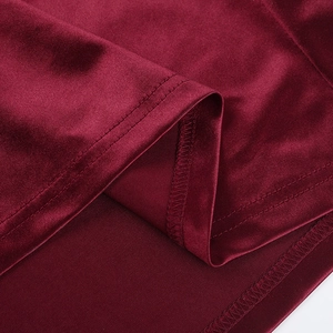 Gros plan de la robe en satin bordeaux montrant les coutures de l'ourlet et le tissu soyeux