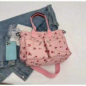 Detailed view of pink cherry print tote bag with multiple pockets and denim jacket