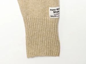 Close-up of beige knit jacket detail with ribbed cuffs and Jeans-New Style woven label