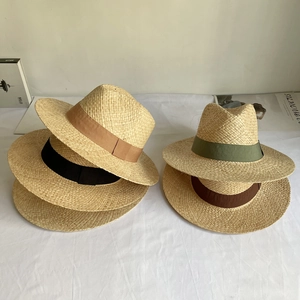 Detail view of woven raffia fedora hats with colored ribbon bands in various neutral tones
