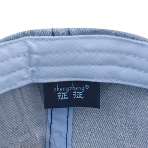 Détail macro de l'étiquette intérieure et des coutures sur la casquette en jean délavé