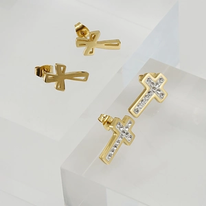 Golden stainless steel cross stud earrings with sparkling crystals on a clear stand