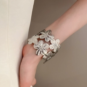 Close-up of a silver metal flower cuff bracelet worn on the wrist for a stylish look
