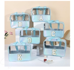 Dettaglio di trousse olografiche azzurre con toppe a lettere glitterate dorate in mostra