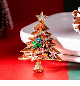Macro shot of gold-plated Christmas tree brooch with colorful rhinestones and enamel details
