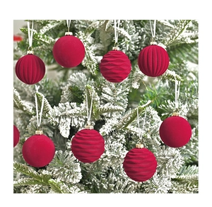 Detail of red velvet Christmas ornaments with diverse textures hanging on a snowy tree