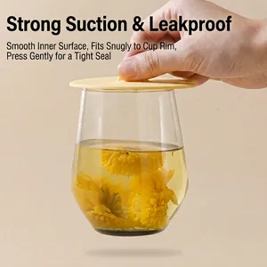 Cream silicone cup lid with handle showing strong suction on a clear glass mug