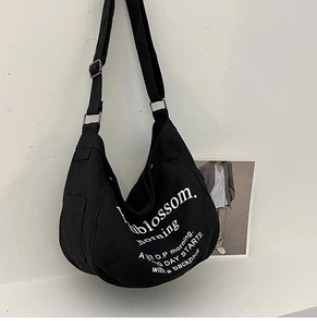 Détail d'un sac cabas noir en toile avec poche latérale et boucle de réglage en métal