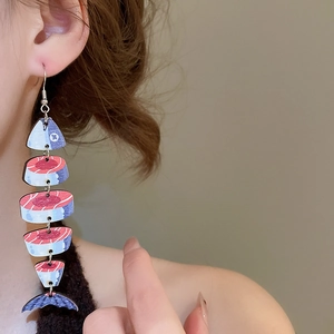Macro side view of ethnic long wooden fish pendant earrings worn on model's earlobe
