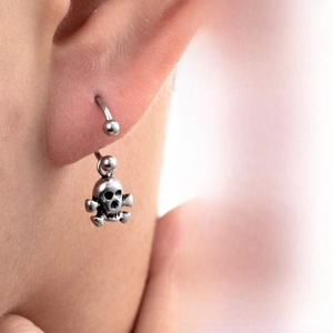 Close-up of punk style titanium steel C-hoop earring with a vintage skull pendant