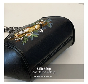 Close-up of animal embroidery and reinforced stitching on black shell bag with chain