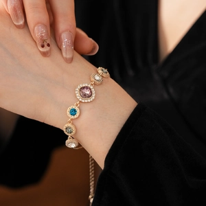 Close-up of vintage gold bracelet with colorful round gemstones and sparkling crystals