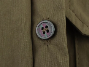 Macro shot of marble-textured resin buttons on dark olive green woven fabric shirt