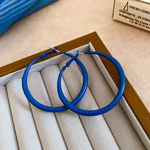 Minimalist Klein blue hoop earrings displayed on a grey jewelry tray with vintage style