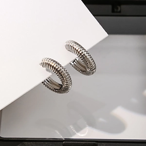 Détail de boucles d'oreilles créoles torsadées argentées avec texture spirale sur carte