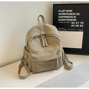 Detail of beige corduroy mini backpack texture on a white marble surface
