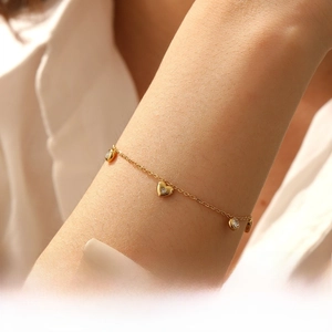 Detailed view of a gold-plated stainless steel chain bracelet with heart and round charms