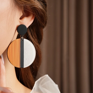 Détail de boucles d'oreilles rondes en bois et résine portées par un mannequin chic