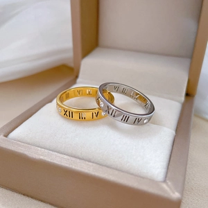 Close-up of gold and silver Roman numeral rings with zircon inlay in a jewelry box