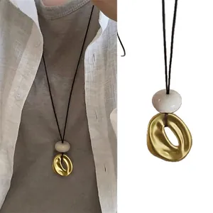 Collana lunga minimalista in resina con anello dorato traforato e cordino nero