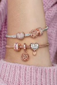 Nahaufnahme von versilberten und rosévergoldeten Charm-Armbändern mit Herzanhängern