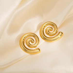 Macro shot of minimalist gold spiral earrings on elegant champagne silk fabric