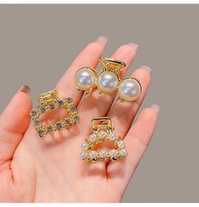 Macro detail of three mini gold alloy hair claws with pearls and rhinestones