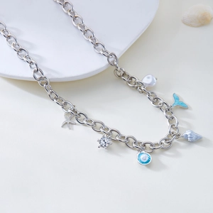 Close-up of silver chain necklace with starfish, shell, and pearl ocean themed charms