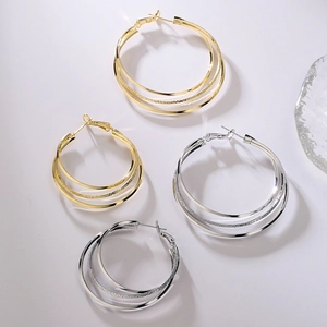 Three-layer geometric gold and silver hoop earrings set on professional white background