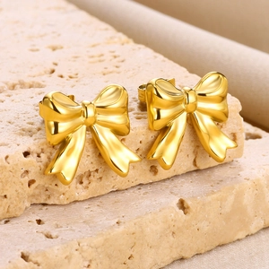 Macro shot of gold bow stud earrings with a satin finish on a stone display