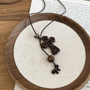 Détail du collier avec croix léopard, pendentif nœud et perles en résine rétro
