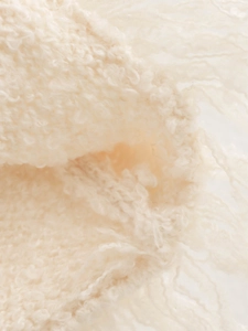 Macro shot of soft beige knit fabric texture with delicate fringe and wool-like fibers