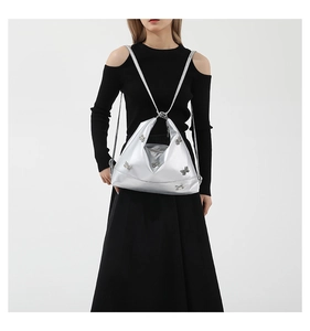 Close-up of a glossy silver shoulder bag featuring a decorative butterfly on the model