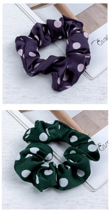 Detailed view of polka dot satin scrunchies in dark purple and deep green colors
