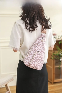 Detail of pink leopard print crossbody bag with multi-zipper pockets and jacquard strap