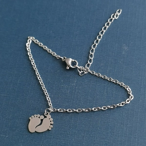 Polished stainless steel bracelet featuring double baby feet charms and lobster clasp