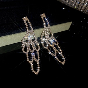 Macro shot of rose gold tassel earrings with sparkling rhinestones on dark background