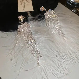 Sparkling long tassel earrings with white feathers and rhinestones in silver finish