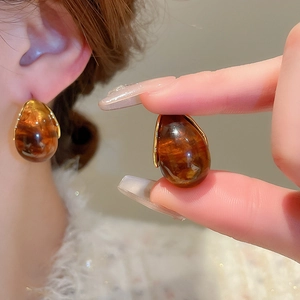 Macro detail of amber resin water drop earrings with vintage gold metal accents