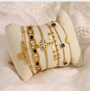 Détails d'un ensemble de bracelets dorés avec breloques croix et cristaux noirs