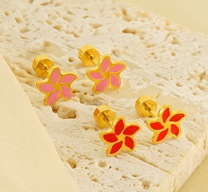 Close-up of pink and red enamel flower stud earrings with gold screw backs on stone